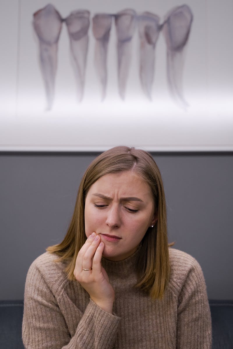 Une femme adulte inquiète et souffrant d'un mal de dents est assise dans un cabinet dentaire.